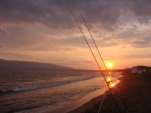 foto di un tramonto con in primo piano le mie canne da surfcasting